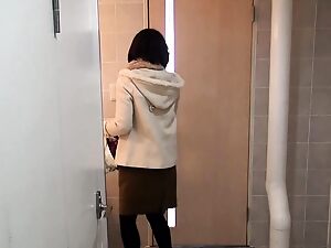 Eine japanische Frau neckt, indem sie in einen Eimer pinkelt.